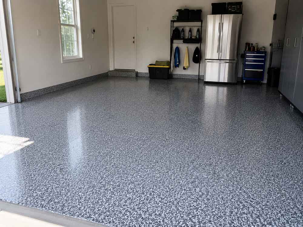 Gray flake epoxy garage floor with cabinets and stainless appliances